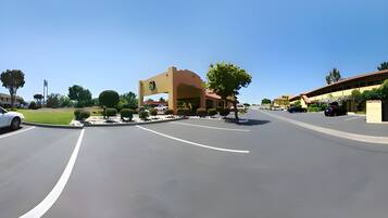 A parking lot with a building featuring a large archway and a sign.