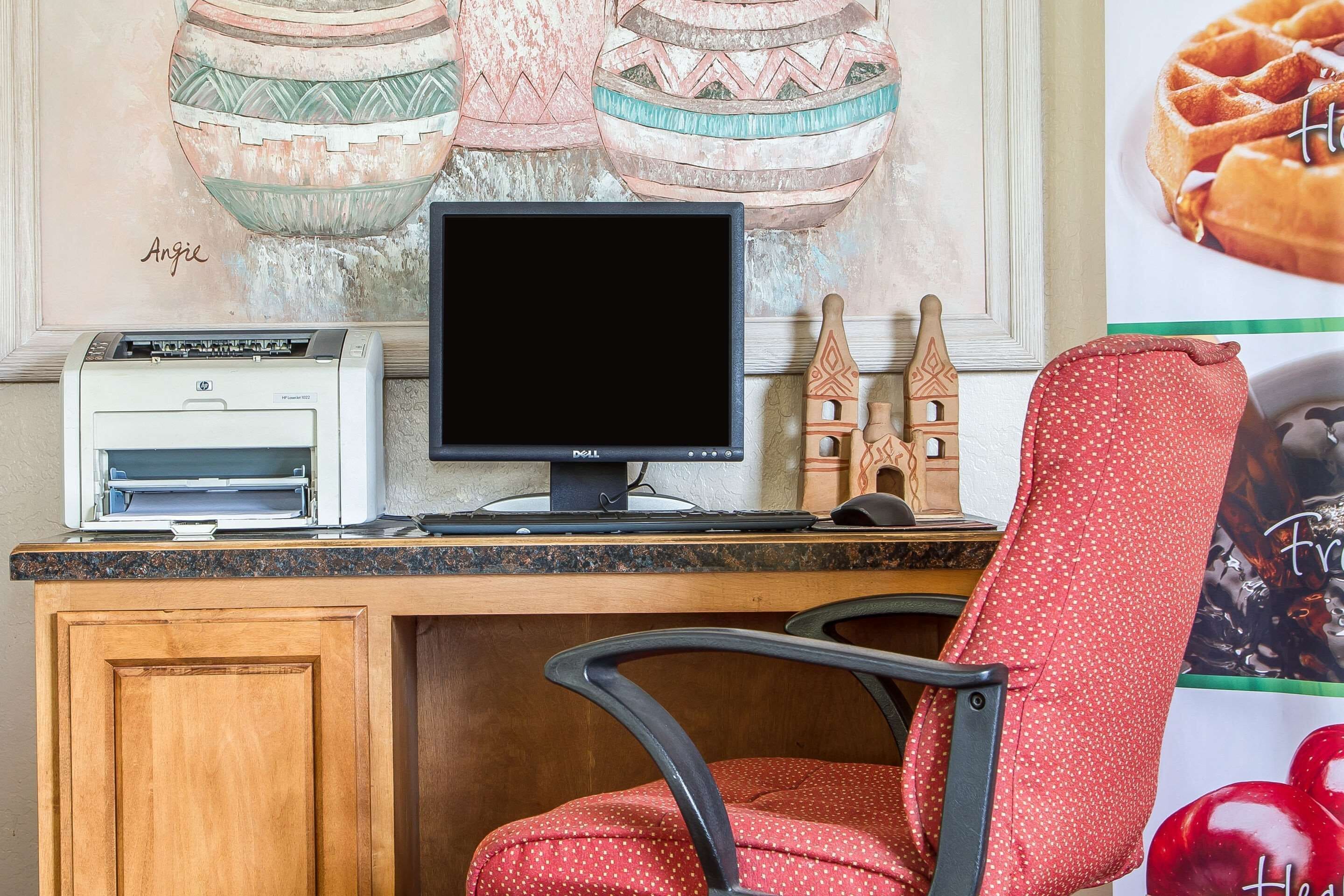 Un espacio de trabajo en casa con una computadora de escritorio, una impresora y una silla de lunares.