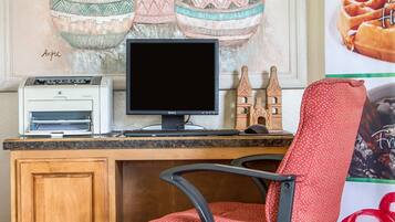 Un espacio de trabajo en casa con una computadora de escritorio, una impresora y una silla de lunares.