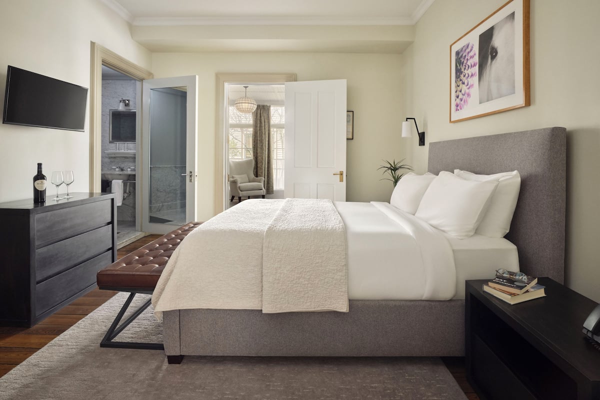 A modern bedroom with a bed, bedside table, and a TV mounted on the wall.