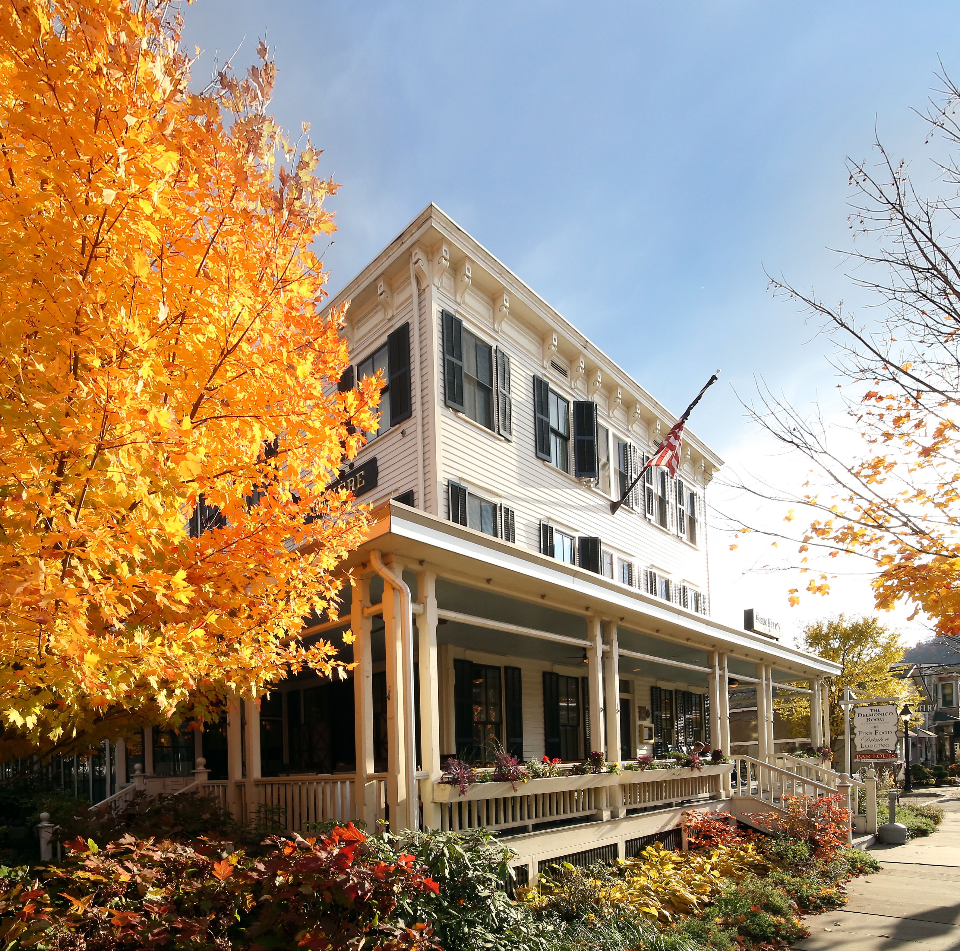 A two-story building with a porch, a flag, and signs indicating a restaurant and lodging.