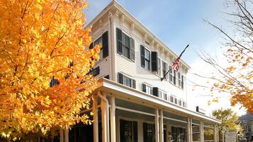 A two-story building with a porch, a flag, and signs indicating a restaurant and lodging.