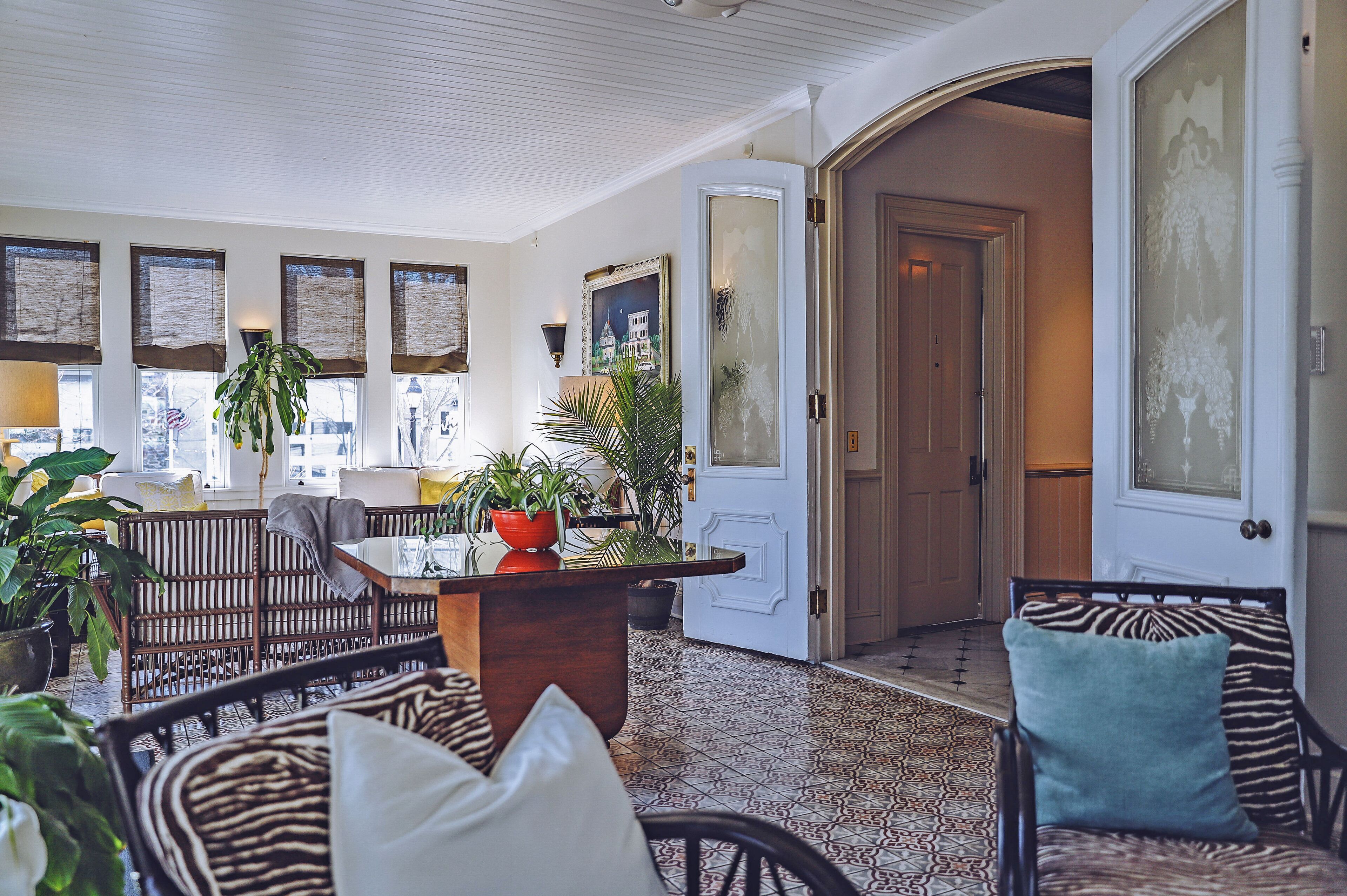 A spacious living area with a high ceiling, large windows, and a variety of seating arrangements including a sofa, chairs, and a table.