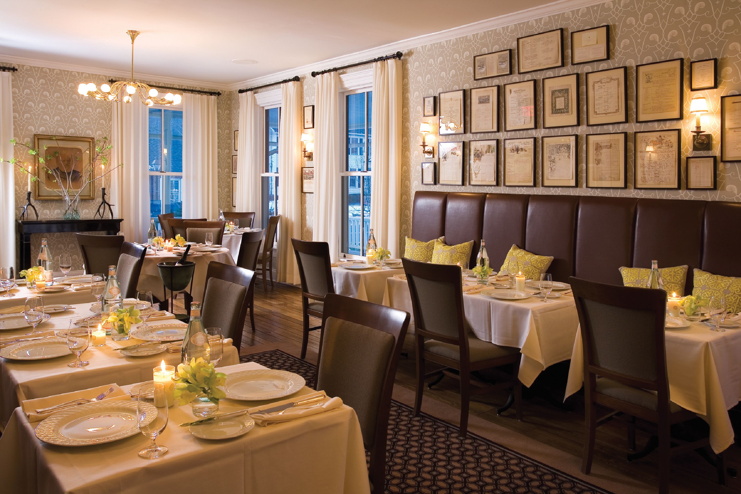 A formal dining room with tables set for service, a piano, and framed certificates on the wall.