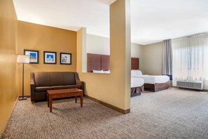 Ein Hotelzimmer mit einem braunen Sofa, einem kleinen Tisch, einem Bett mit weißer Bettdecke und einem großen Fenster mit Vorhängen.