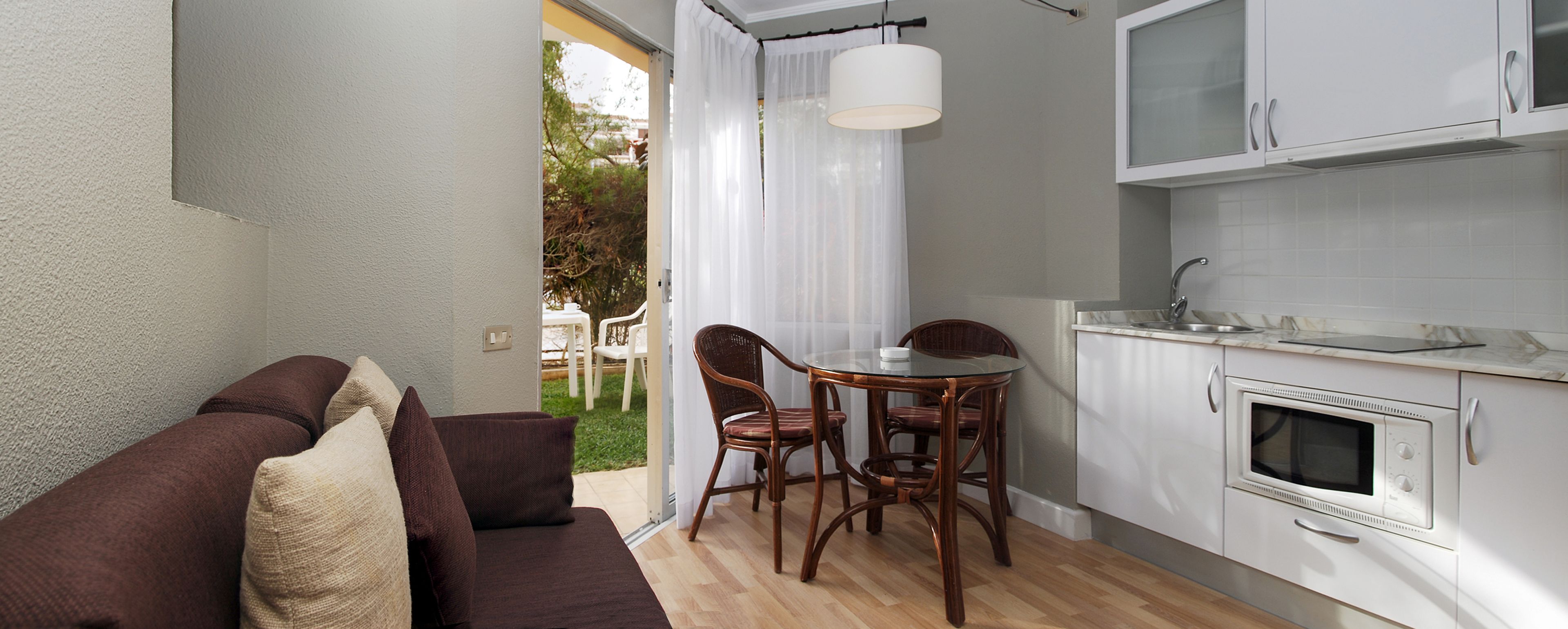 Une cuisine compacte équipée d’un four à micro-ondes, d’un évier et d’un coin repas avec une table et des chaises.