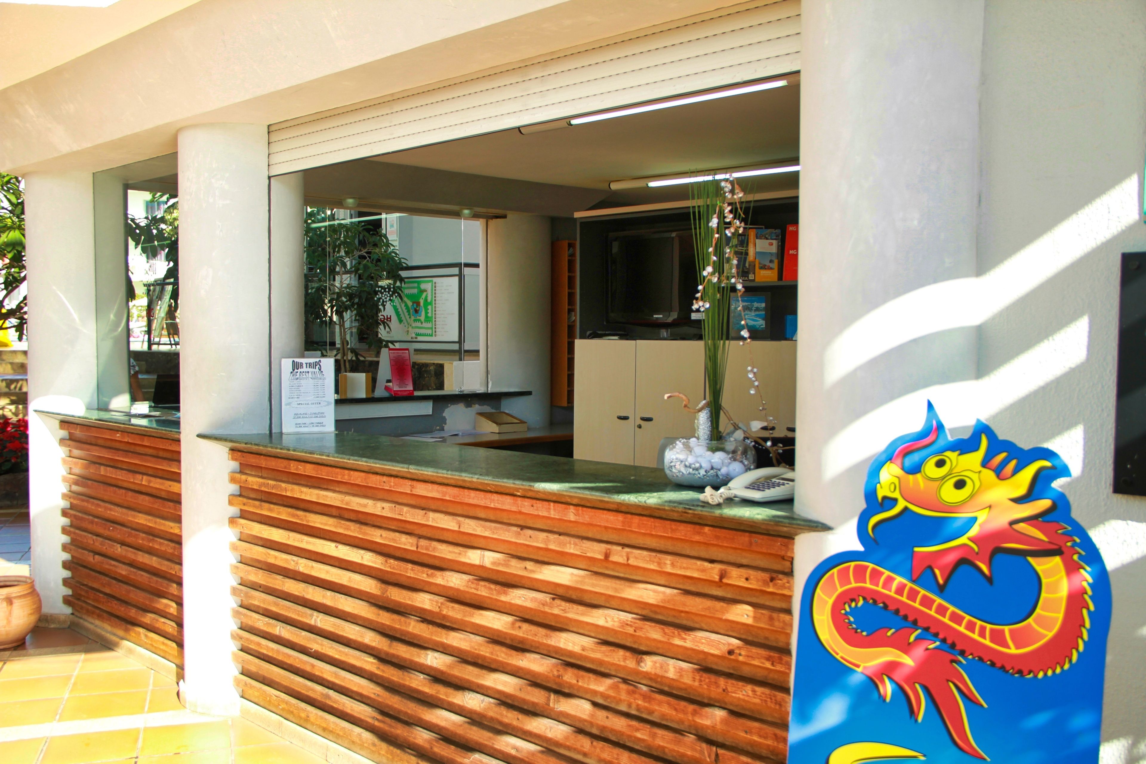 Un mostrador de recepción con diseño de listones de madera, una ventana de vidrio y un cartel.