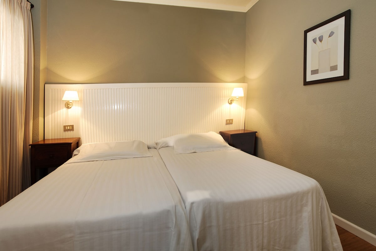 A double bed with two bedside tables, a headboard with integrated lighting, and a framed picture on the wall.