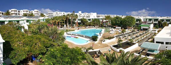 A resort with a large swimming pool, multiple lounge areas, and a view of the surrounding buildings. - Apartamentos HG Lomo Blanco (Tías)