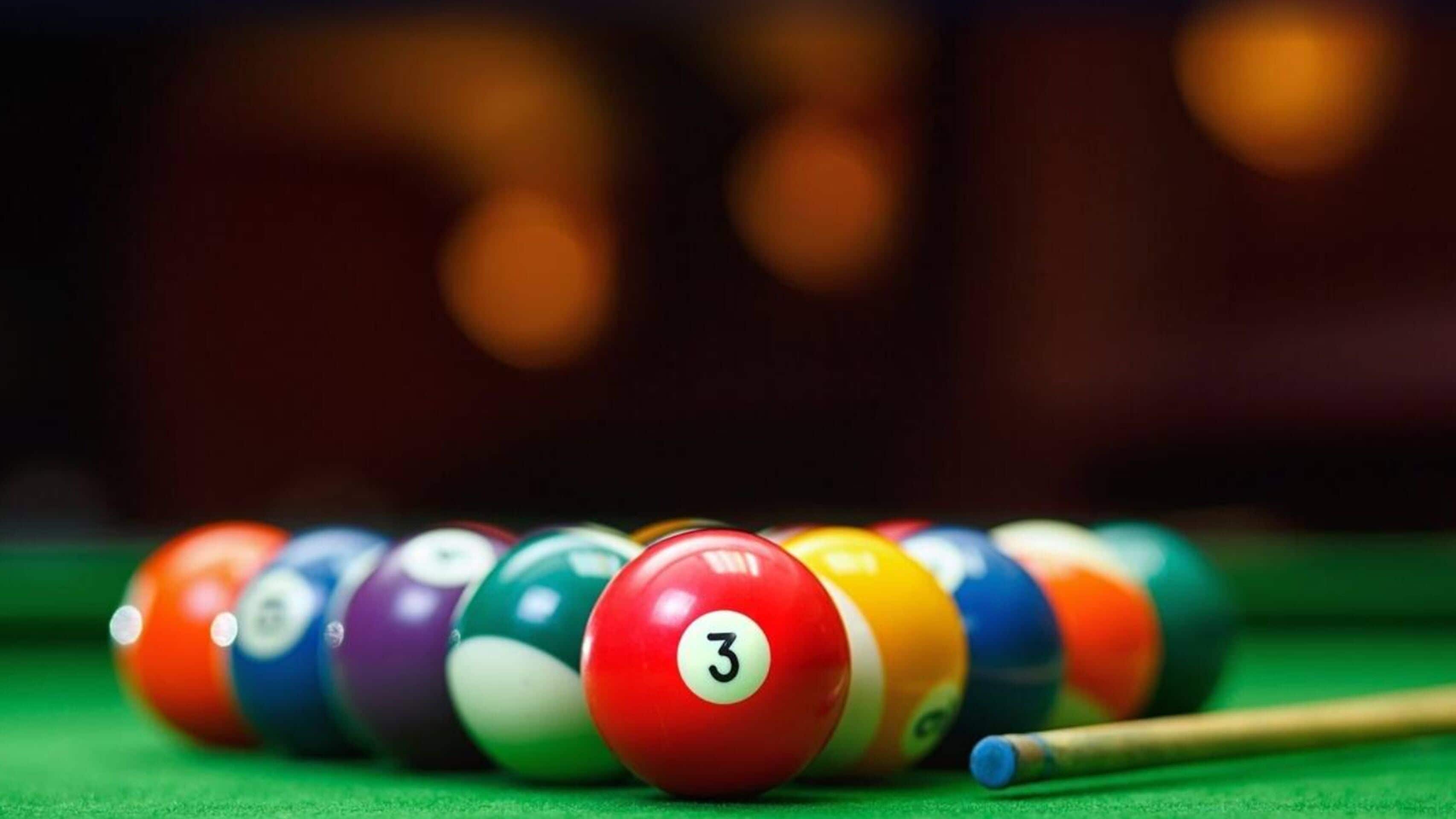 A close-up of a pool table with numbered billiard balls in focus.