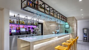 A modern bar area with a bar counter, stools, and a variety of liquor bottles. - Apartamentos HG Lomo Blanco (Tías)