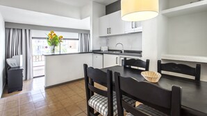 A modern kitchen with a dining area, featuring a black dining table, chairs, and a hanging light fixture. - Apartamentos HG Cristian Sur (Arona)