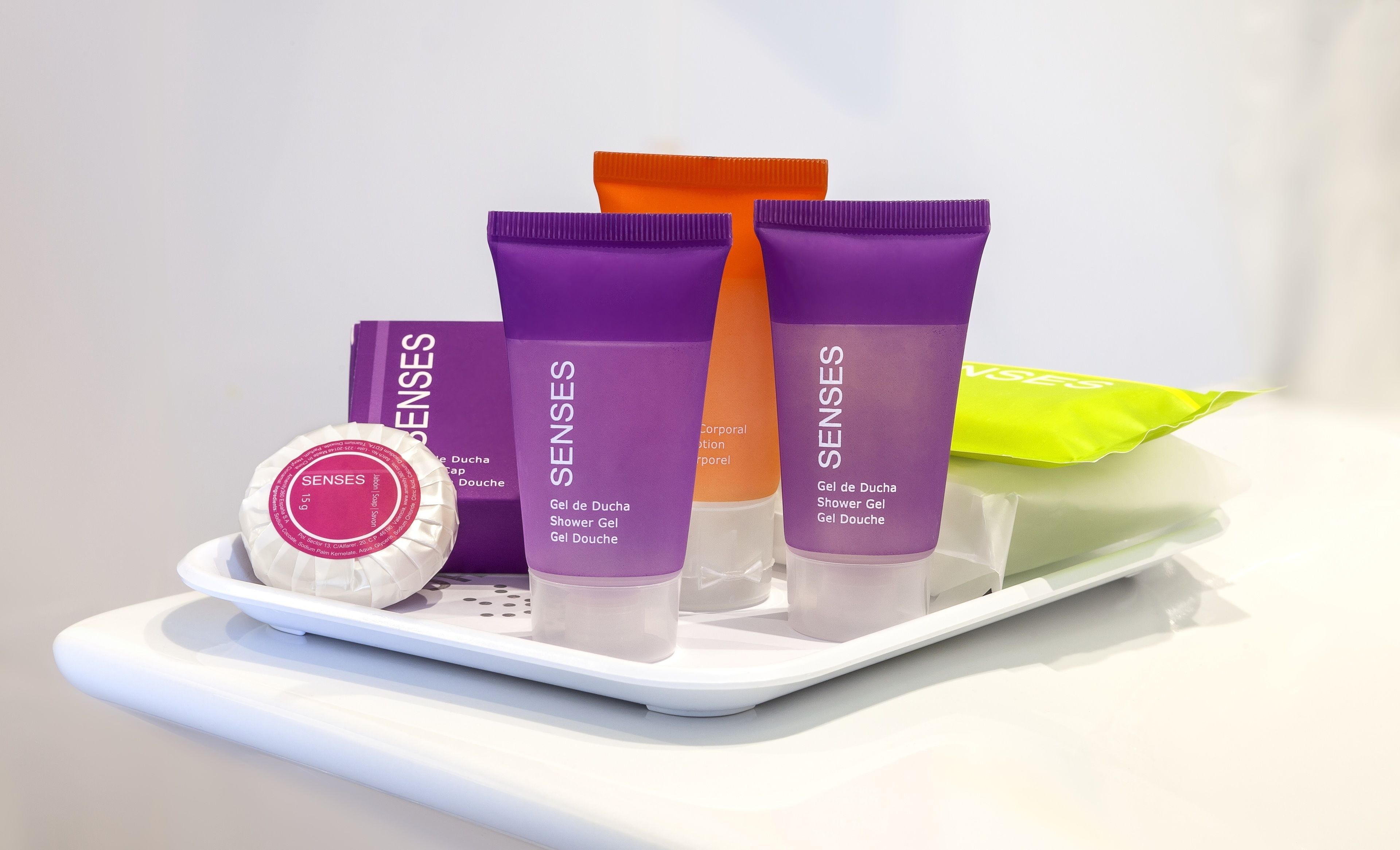 Tarjottimella oli erilaisia hygieniatuotteita, kuten violetti pullo, jossa oli teksti ”Senses”, oranssi pullo ja vihreä paketti.