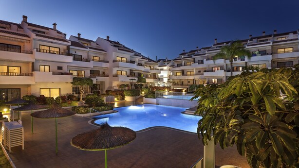 A hotel courtyard with a swimming pool, multiple balconies, and lush greenery. - Apartamentos HG Cristian Sur (Arona)