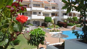 A hotel with multiple floors, outdoor swimming pool, and lounge areas with umbrellas. - Apartamentos HG Cristian Sur (Arona)