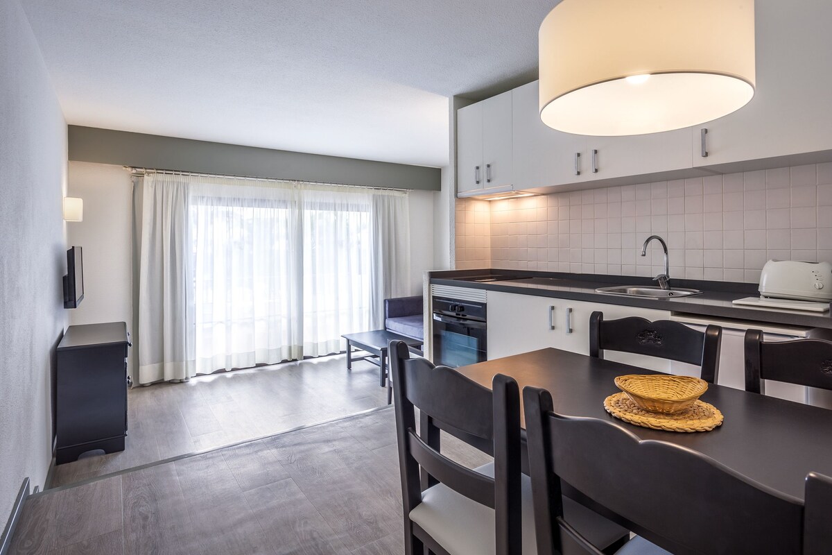 A compact kitchen with a dining area, a built-in oven, a sink, and a toaster.