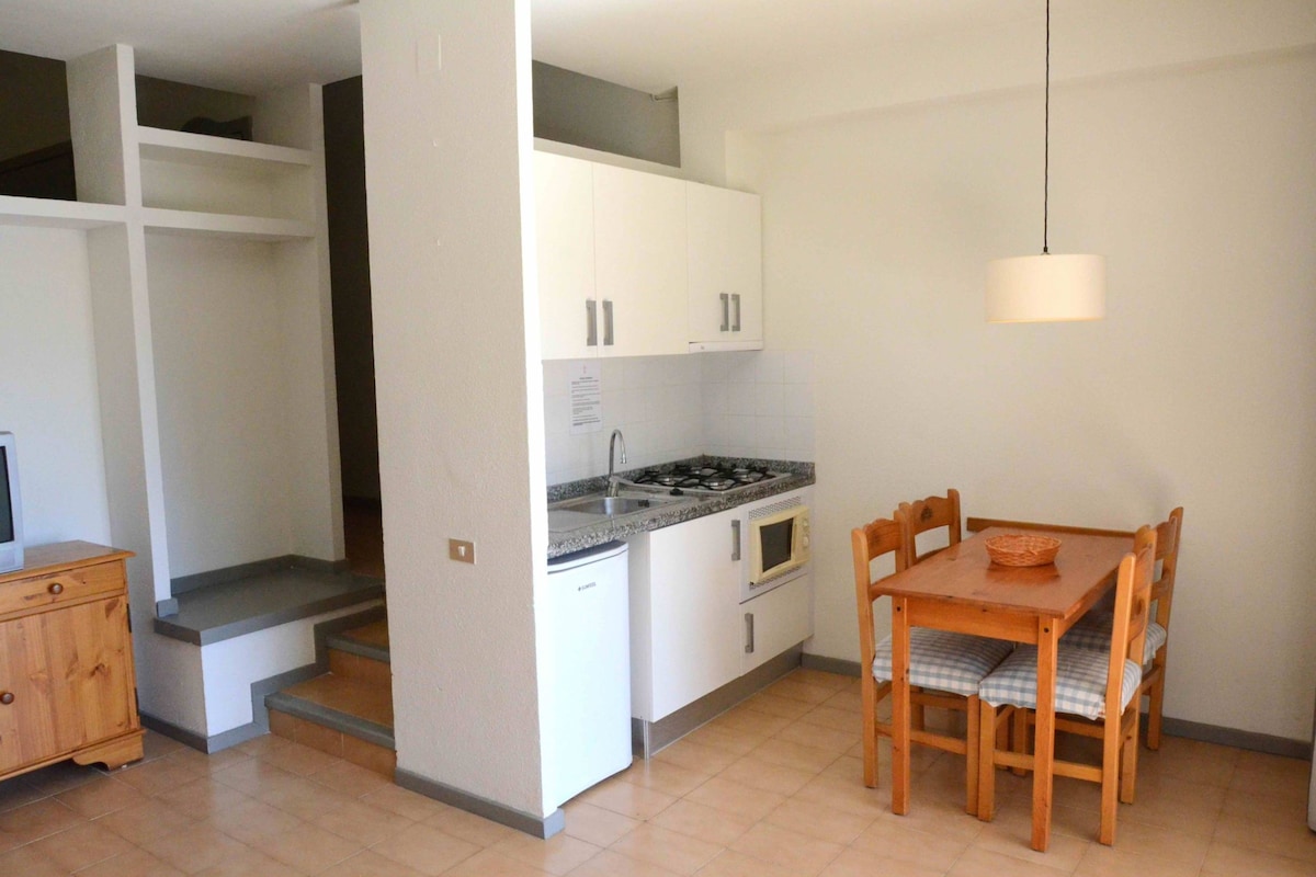 A compact kitchen with white cabinets, a microwave, a stove, and a dining table with chairs.