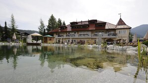 Un hotel con un edificio grande, un estanque y zonas de estar al aire libre.