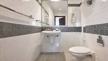 Un baño pequeño con lavamanos blanco, inodoro y espejo.
