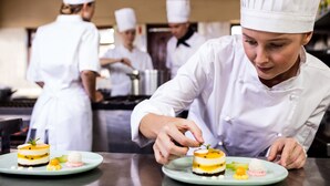 A chef preparing desserts in a professional kitchen with other chefs in the background. - Hotel Calysea Tropea - Breakfast & Brunch - Until 13-00 Included - Free Private Parking (Tropea)