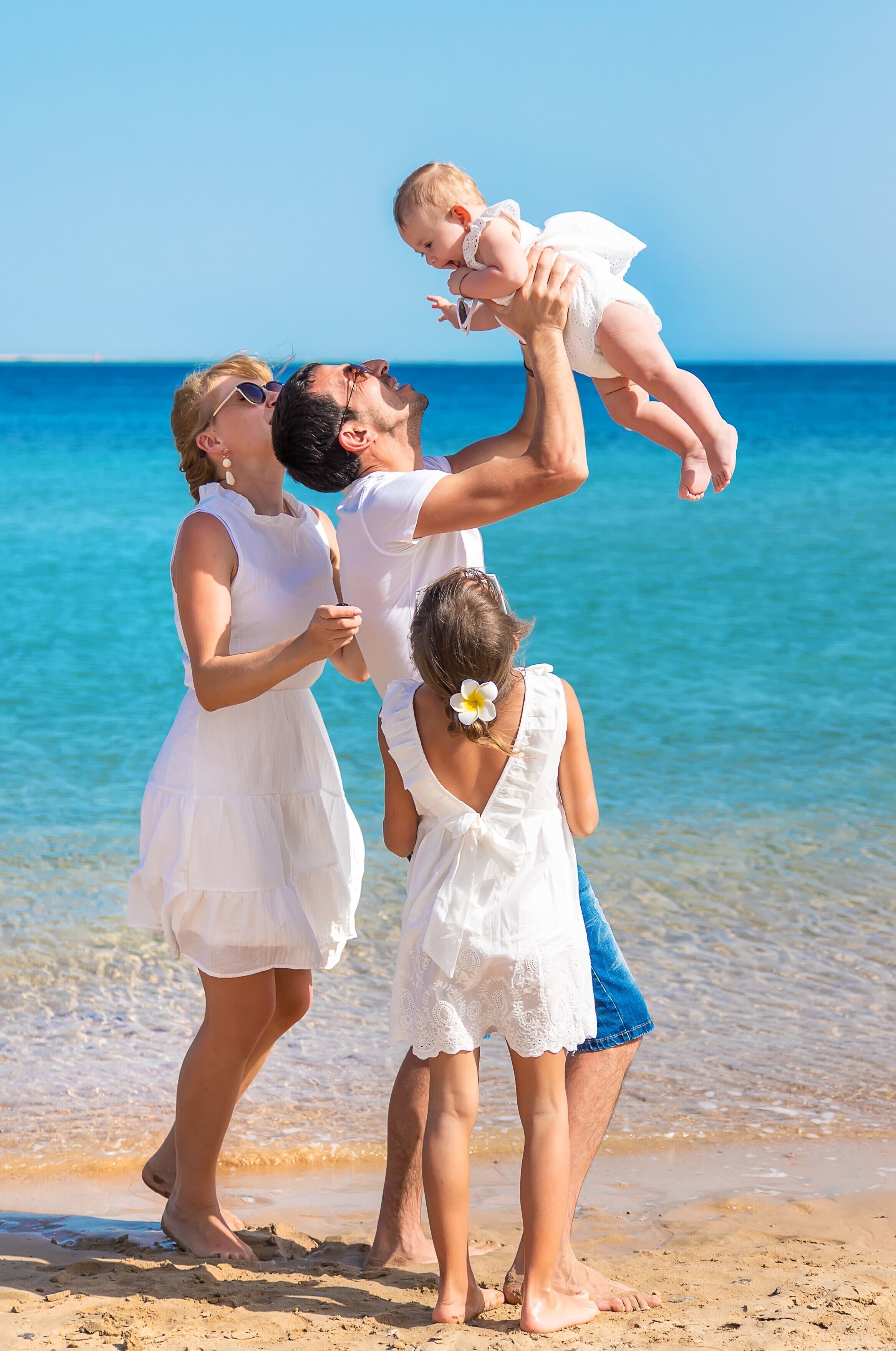 Una familia en la playa, con agua azul cristalina y una orilla arenosa.