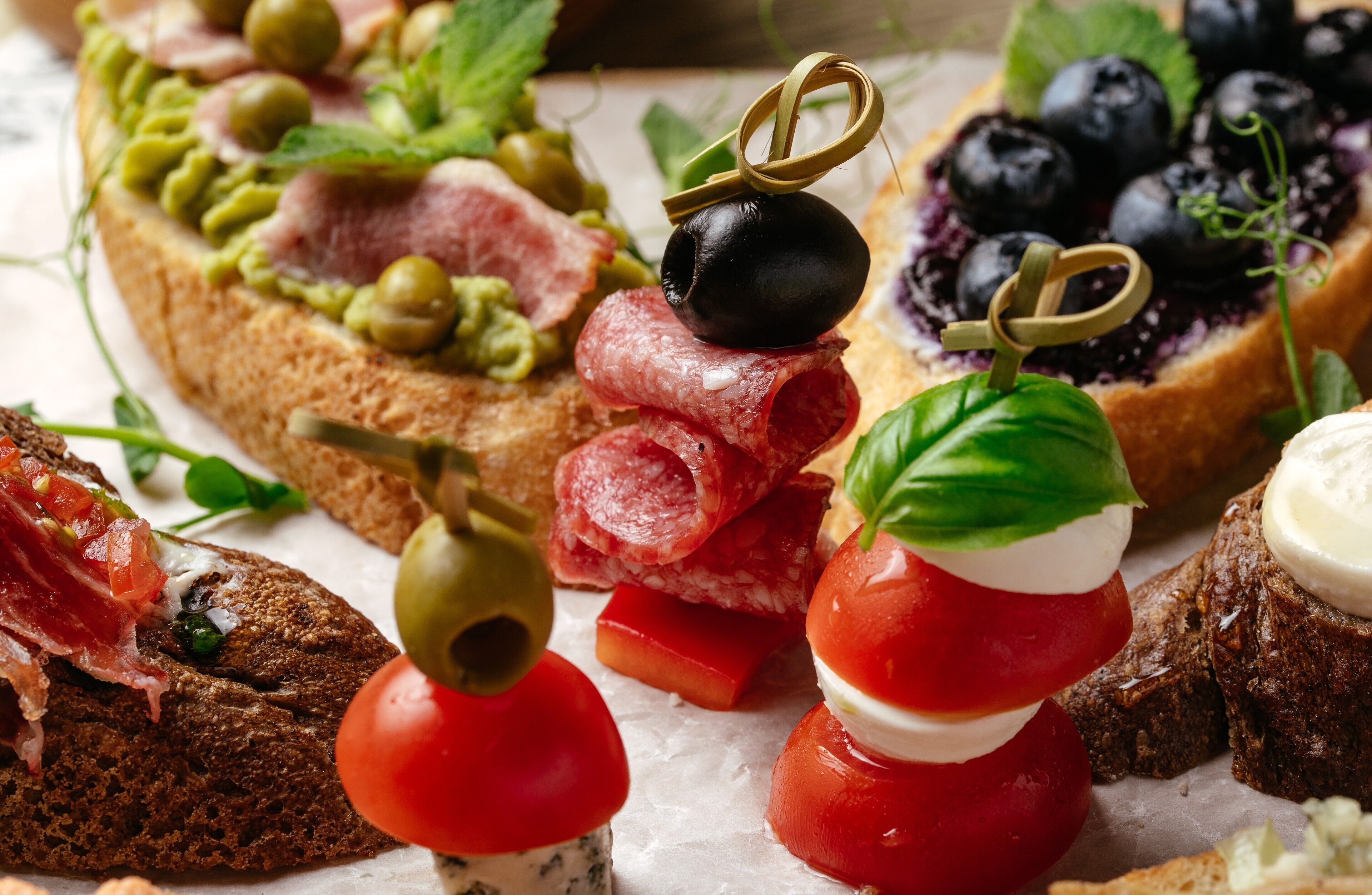 Una variedad de aperitivos, como bruschetta, aceitunas y queso.