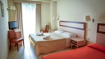 Una habitación de hotel con cama, un escritorio con silla, televisión y ventana con cortinas.