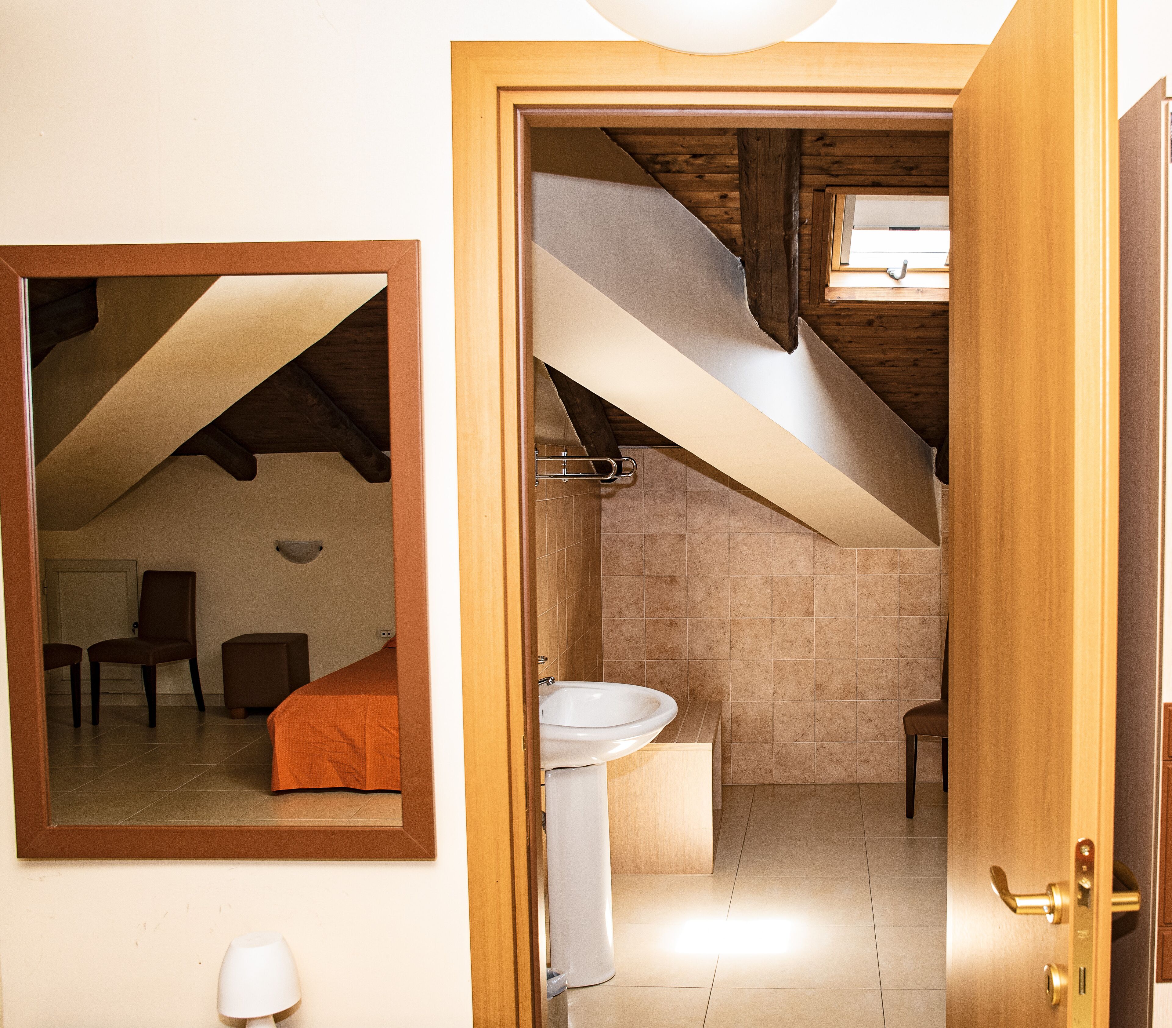 Een kamer met een houten plafond, een wit wastafelmeubel en een spiegel aan de muur.