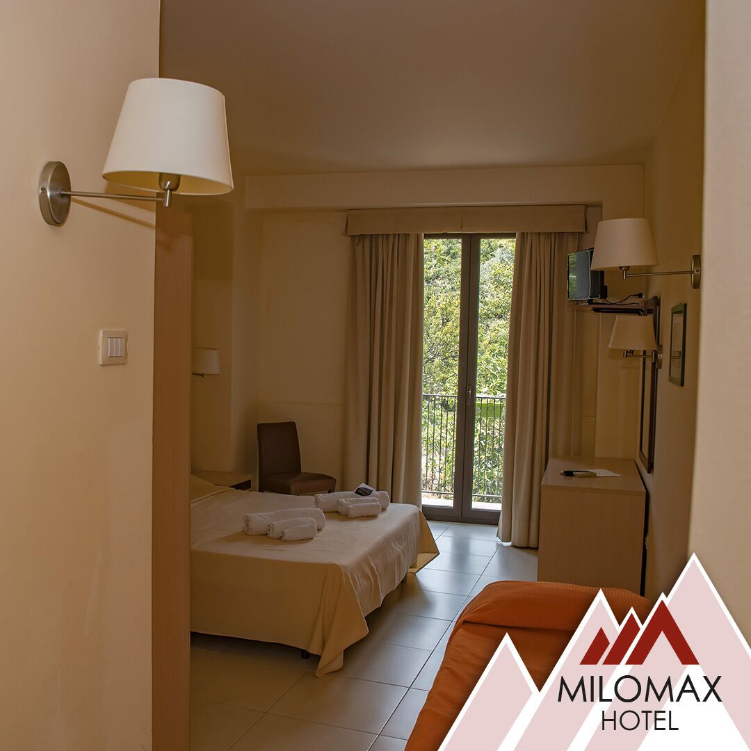 Habitación de hotel con cama, una silla, un escritorio y una ventana con cortinas.