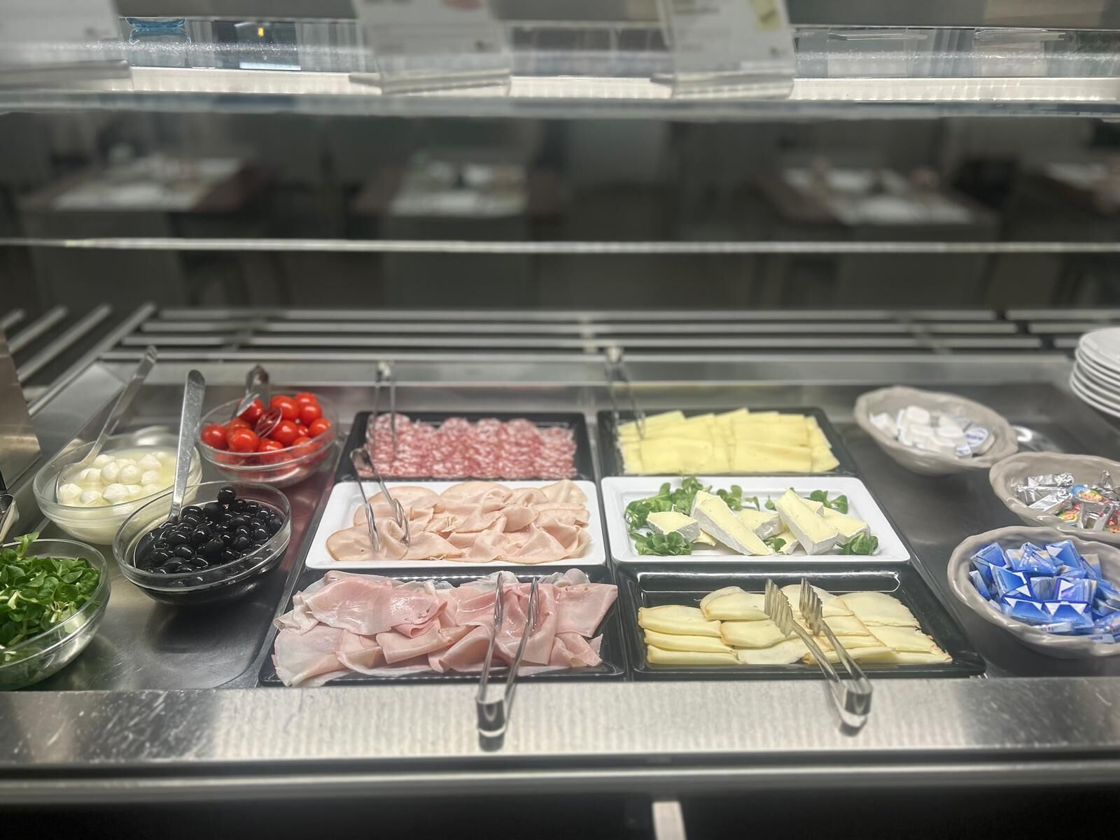 A buffet with various food items including meats, cheeses, and vegetables.