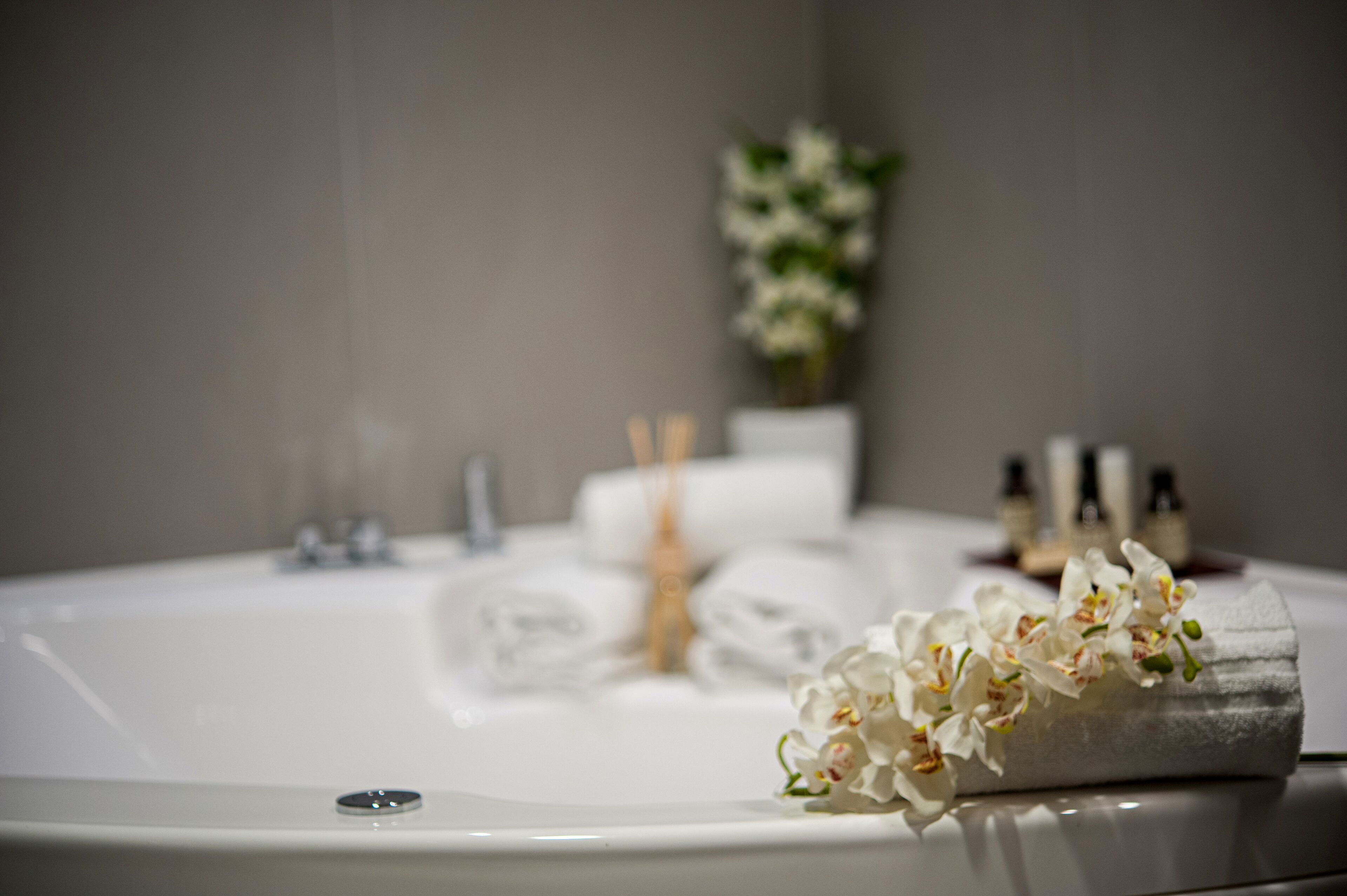 A bathroom with a bathtub, a towel, and a bouquet of white flowers.