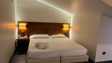 Une chambre d’hôtel moderne avec un lit bien fait, des lampes de chevet et une tête de lit en bois.