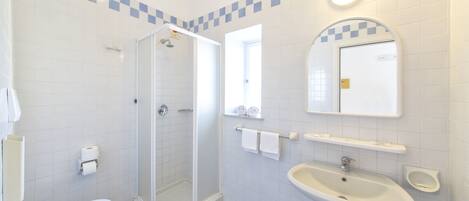A bathroom with a toilet, a glass-enclosed shower, a sink, and a mirror.