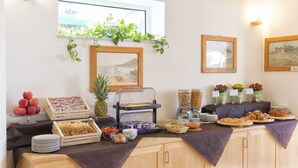Ein Frühstücksbuffet mit Früchten, Gebäck und einem Saftspender.