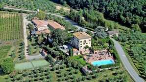 An aerial view of a property with a swimming pool, tennis court, and vineyard. - Villa Curina Resort (Castelnuovo Berardenga)