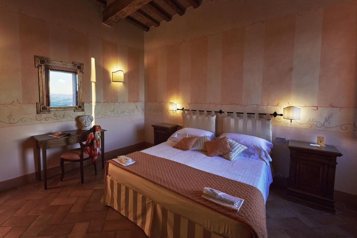 Una habitación de hotel con una cama, un escritorio, una silla y una mesita de noche.