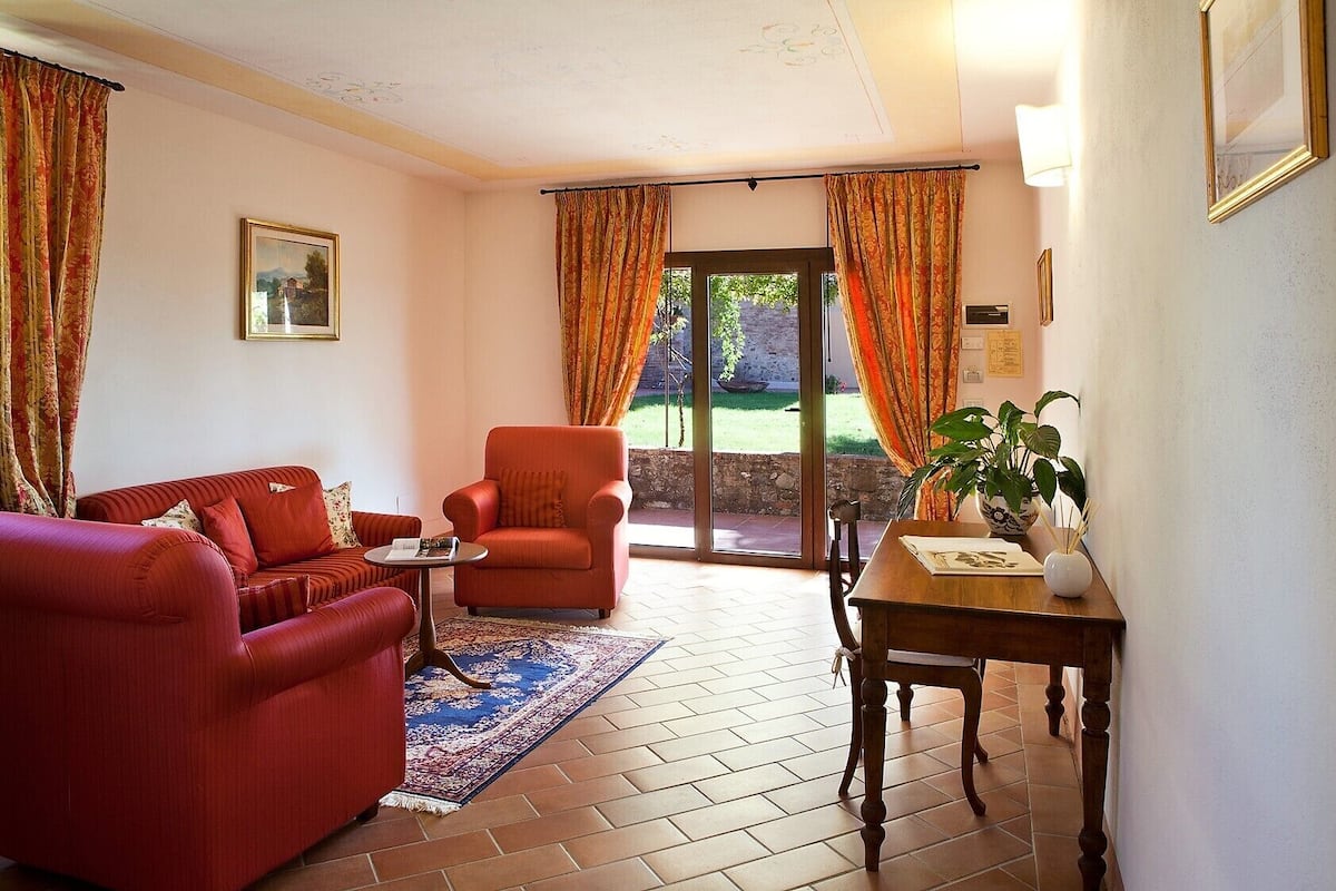 Una sala de estar con un sofá rojo, un sillón rojo, una mesita y una planta en maceta.