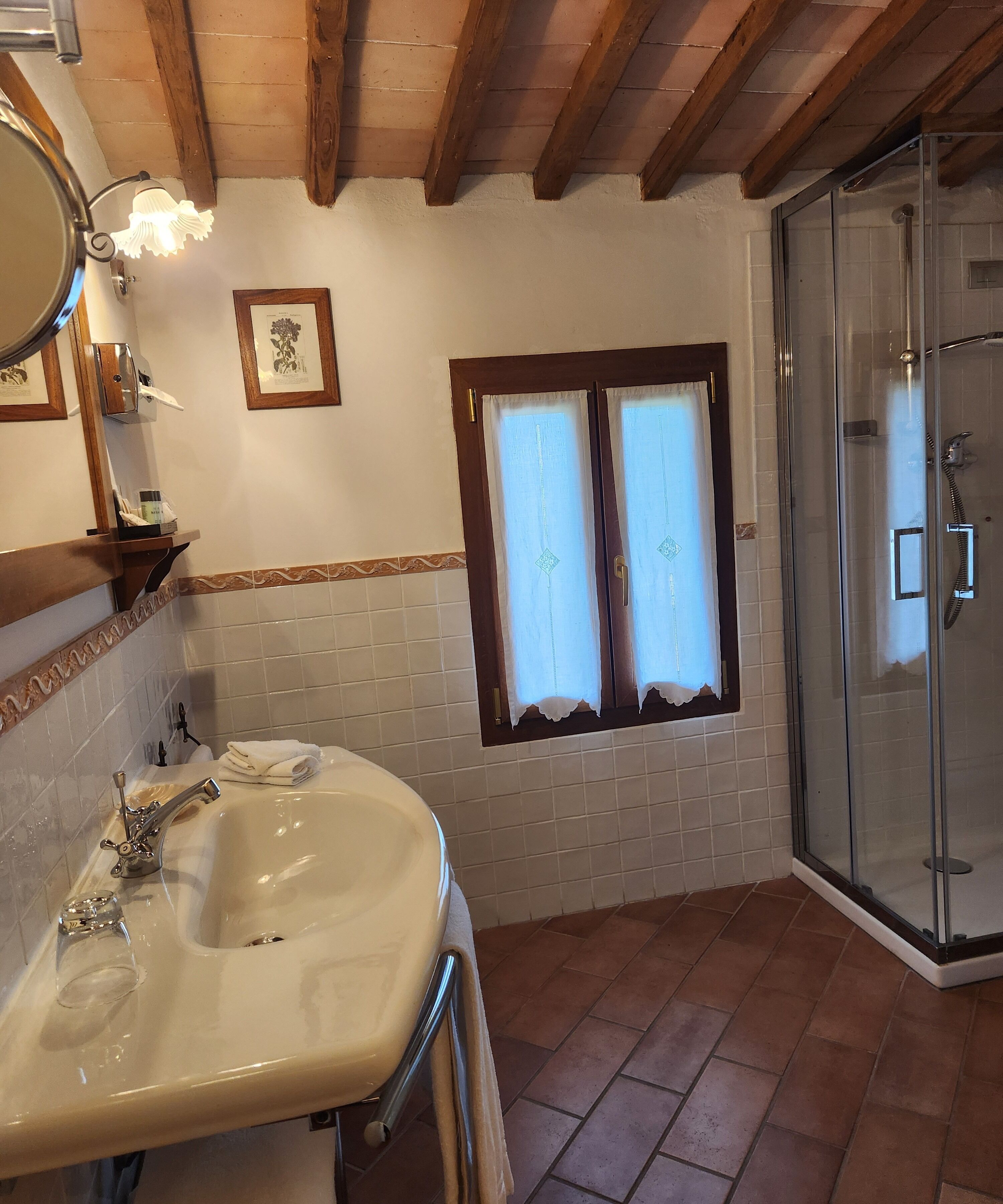 Ein Badezimmer mit Waschbecken, Spiegel, Handtuchhalter, einem gerahmten Bild, Fenster und Dusche.