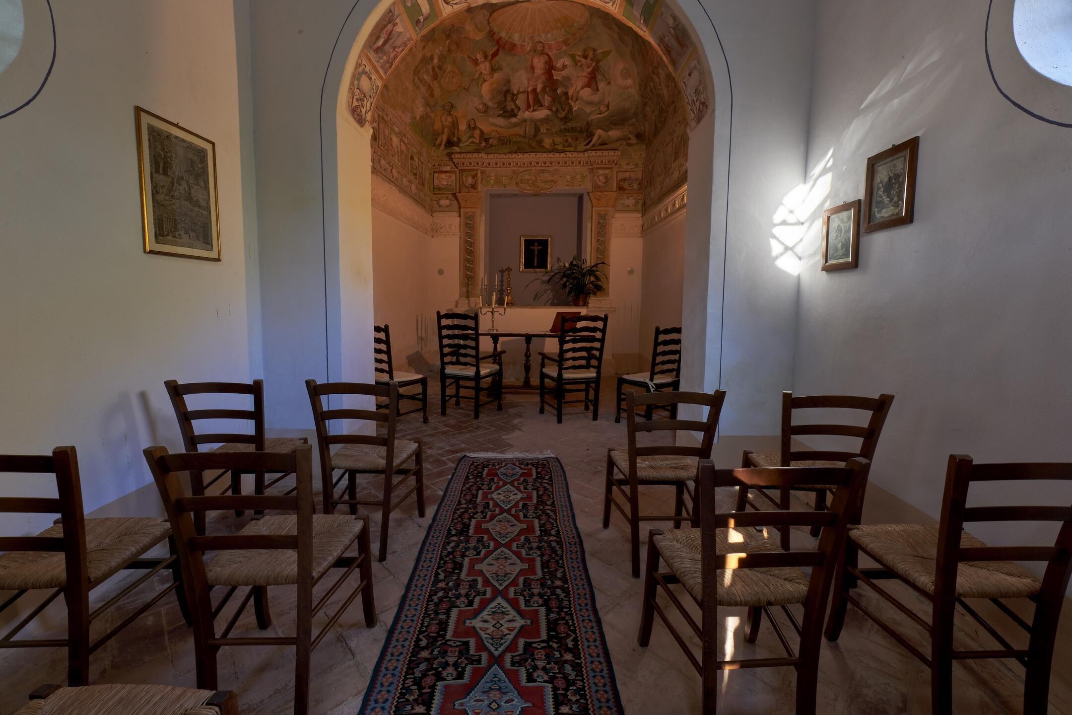 A room with a long, patterned carpet leading to a dining area with wooden chairs and a table.