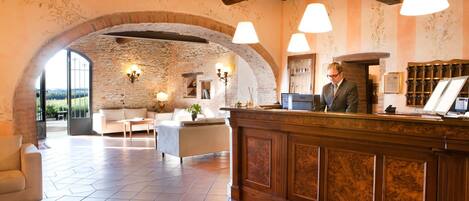 A lobby with a stone archway, a reception desk, and a seating area with a sofa and armchairs.