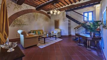 A spacious living area with a high ceiling, a staircase, and a large window.