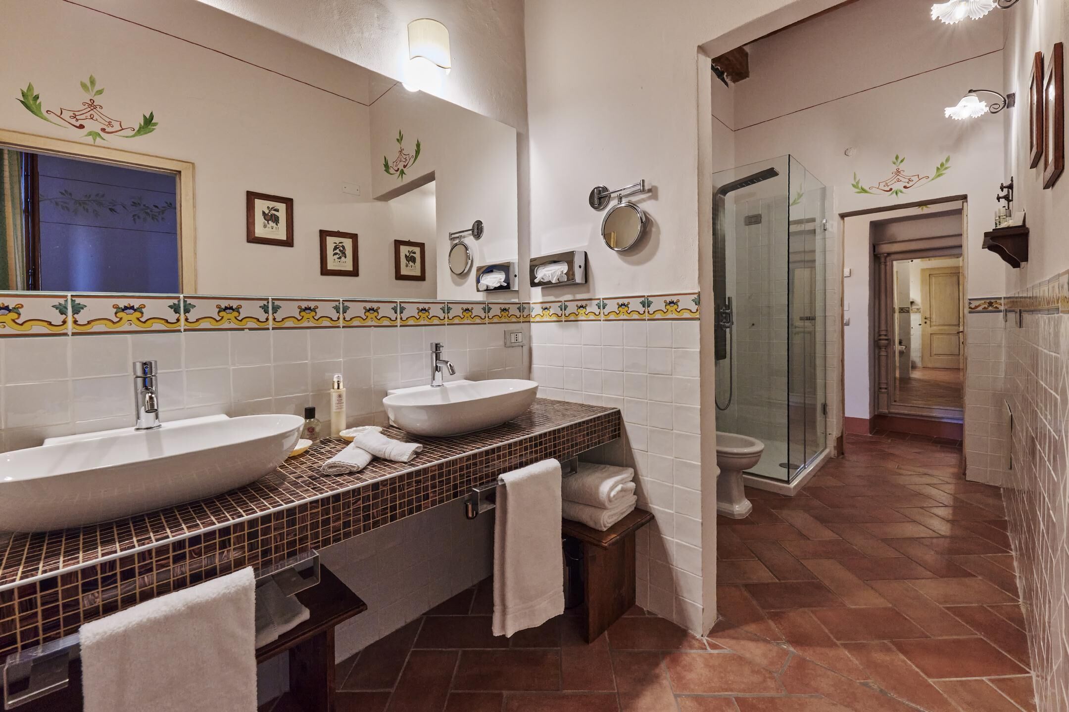 Ein Badezimmer mit zwei Waschbecken, einem Spiegel, einer Dusche und einer Toilette.