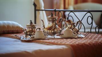 A neatly arranged tea set on a bed with a metal headboard.