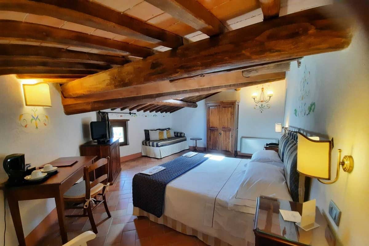 Una habitación acogedora con cama, escritorio y televisor.