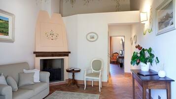 A cozy living room with a fireplace, a sofa, a chair, and a small table with a plant.