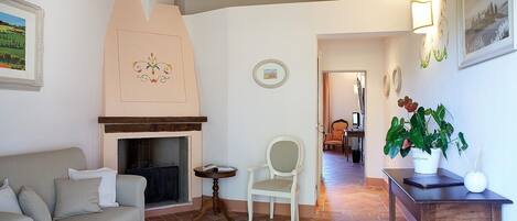 Una sala de estar acogedora con chimenea, un sofá, una butaca y una mesita con una planta.