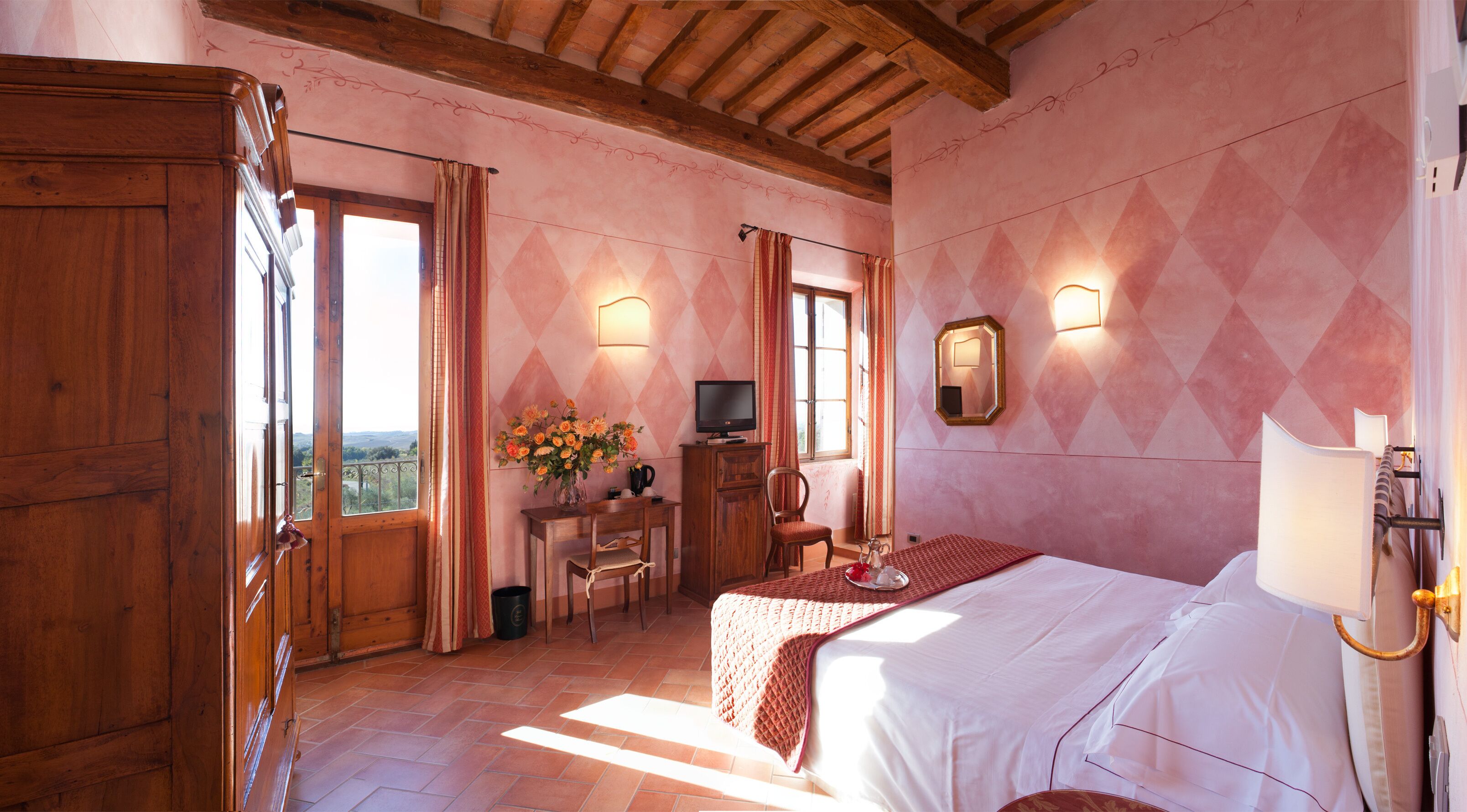 A bedroom with a wooden ceiling, a bed, a desk with a computer, a chair, and a window with curtains.