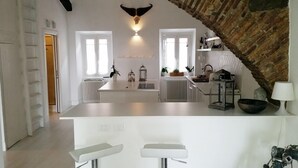 Una cocina moderna con una isla central, armarios blancos y un arco rústico de piedra.