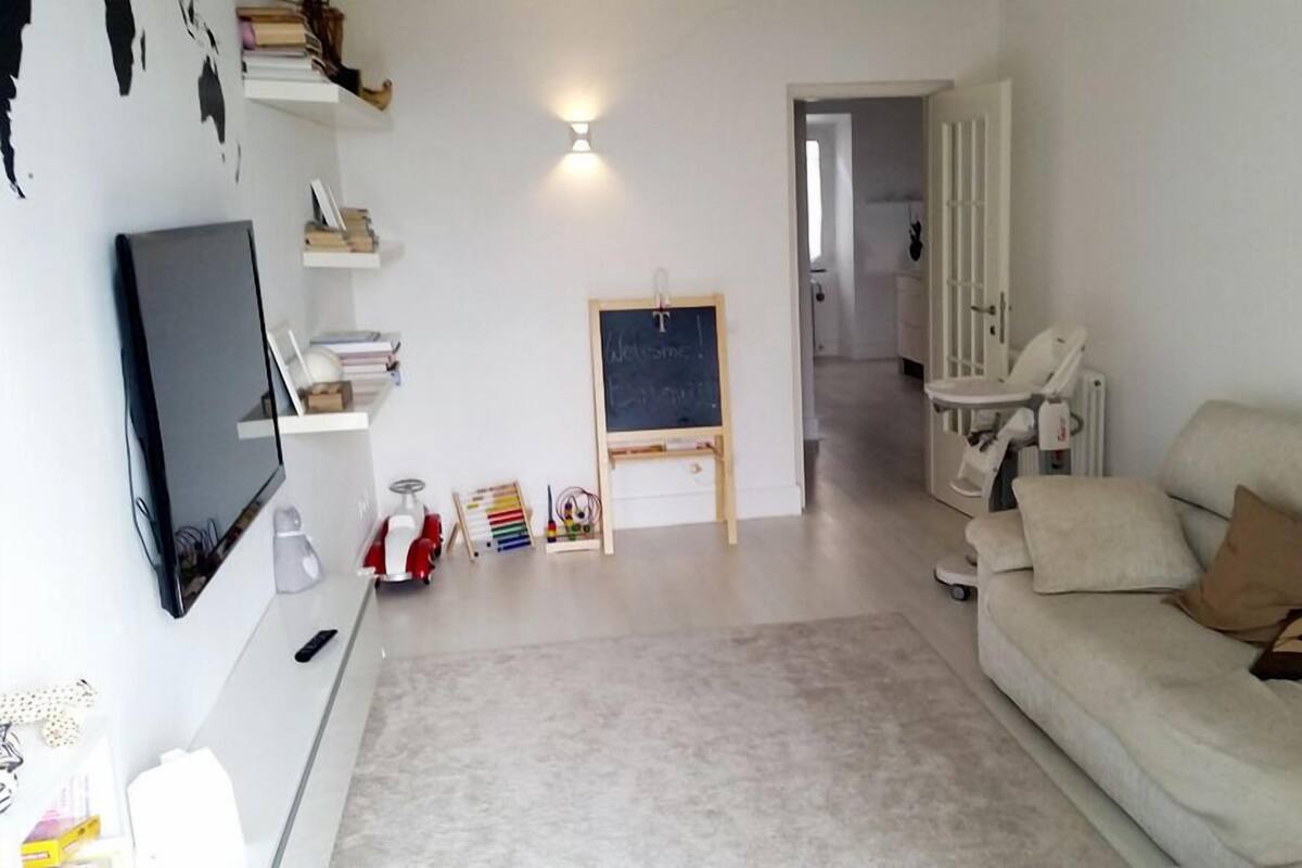 Una sala de estar con televisor, sofá y una pequeña zona de juegos con juguetes y una pizarra.