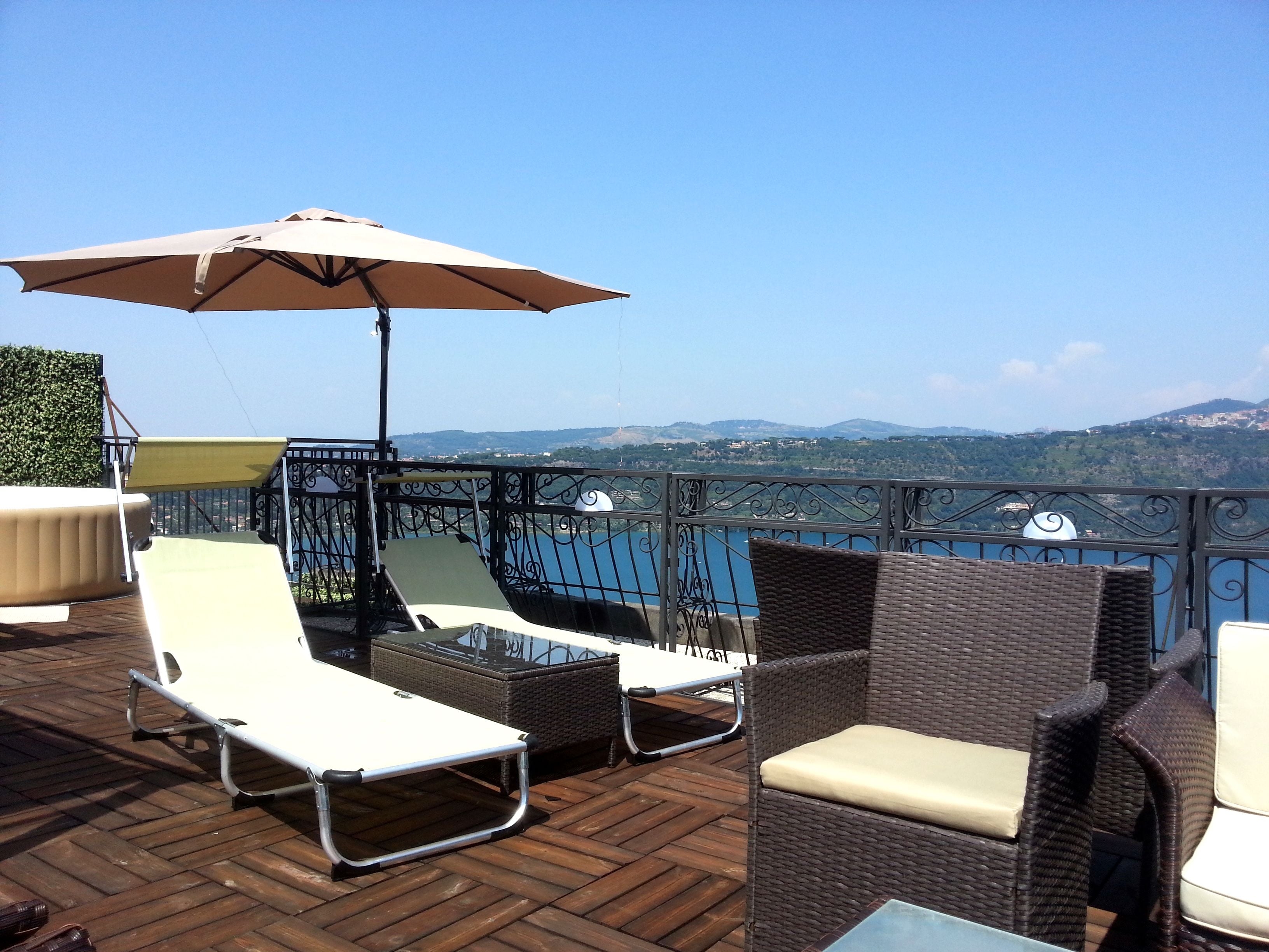 A terrace with wicker furniture, a table, and an umbrella.